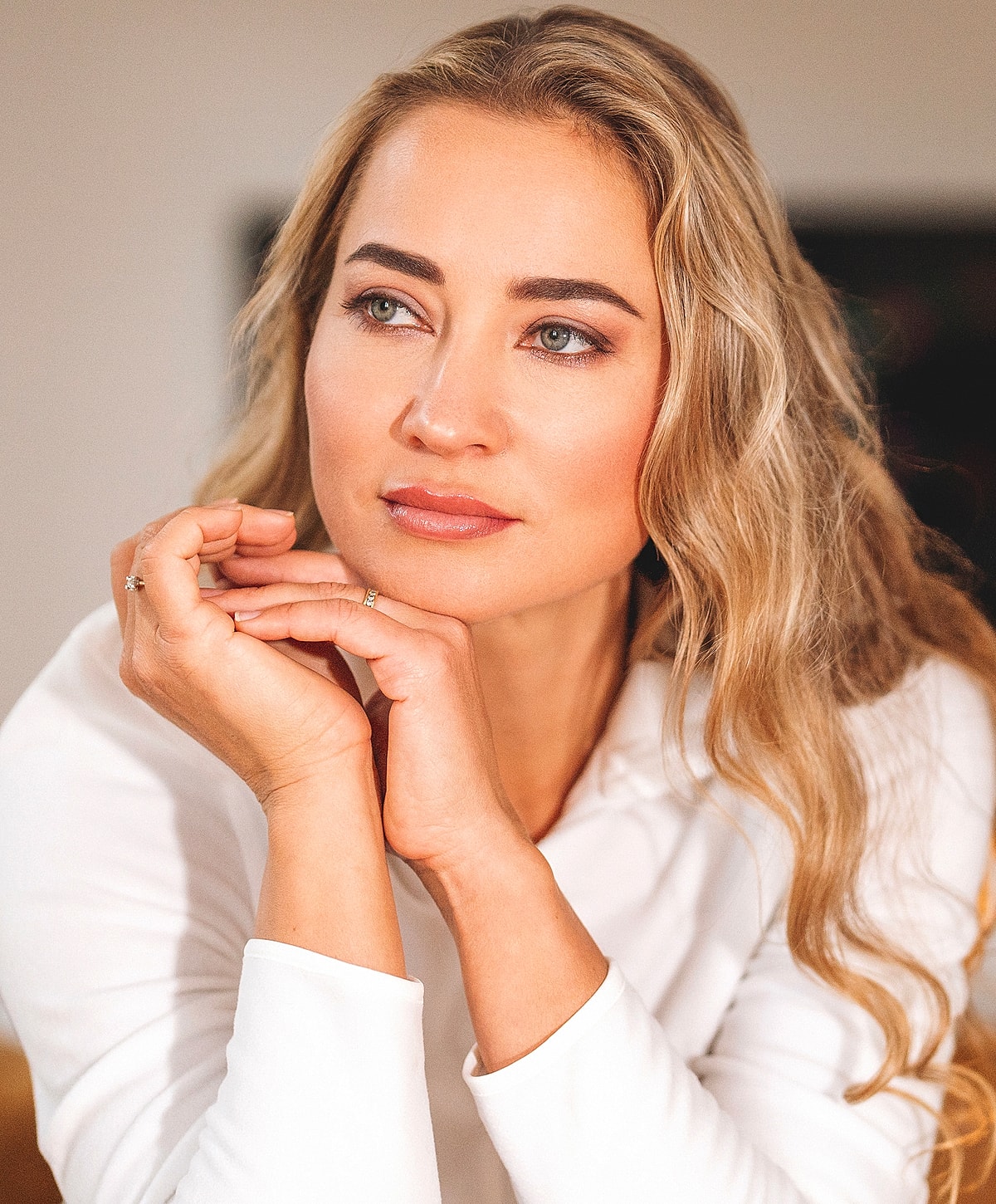 Woman with long hair, thoughtful expression, casual attire.
